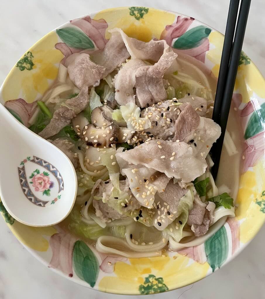 Pork noodles soup in clear broth served with cabbage,sesame seeds